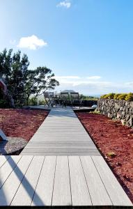 a wooden walkway with a bench and a stone wall at Casas do Tareco in Biscoitos