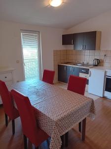 a dining room table with red chairs and a kitchen at Apartman Peace 3 in Međugorje