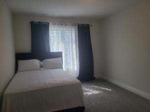 een slaapkamer met een bed en een raam met blauwe gordijnen bij Ensuite Bedroom –Double Bed: Mins from Coburg Beach in Cobourg