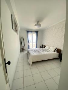 a white bedroom with a bed and a window at Apartamento frente mar in Praia da Vieira