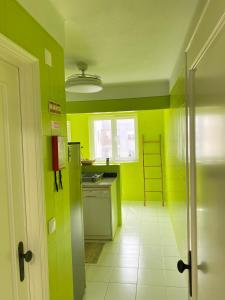 a kitchen with green walls and a white tile floor at Apartamento frente mar in Praia da Vieira
