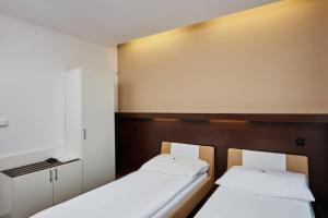 2 Betten in einem kleinen Zimmer mit weißen Wänden in der Unterkunft Hotel Rottal in Otrokovice