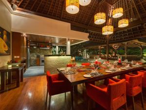 a dining room with a long table and orange chairs at Villa Asta in Seminyak