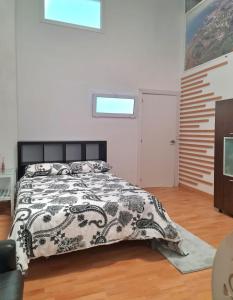 1 dormitorio con 1 cama con edredón blanco y negro en Loft con baño y cocina privados en San Sebastián de los Reyes