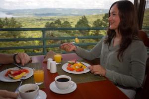 Una donna seduta a un tavolo che fa colazione di Arenal Observatory Lodge & Trails a Fortuna