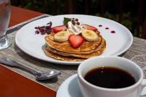 un piatto di pancake con fragole e una tazza di caffè di Arenal Observatory Lodge & Trails a Fortuna