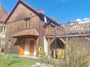 uma casa de madeira com um deque ao lado em Le Chalet du Tanet spa sauna terrasse en Alsace em Soultzeren