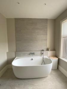 a white bath tub in a bathroom with a window at Beach House in Swanage