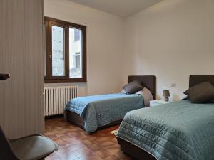 a bedroom with two beds and a window at CASA DEL SOLE in Tremezzo