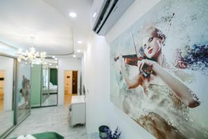 uma pintura de uma mulher a tocar violino numa parede em Park azure sweet apartment by Baku Housing em Baku