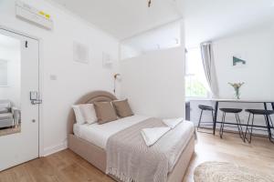 a white bedroom with a bed and a table at Arte Stays Serviced Apartments Premium Studios, Finsbury Park in London