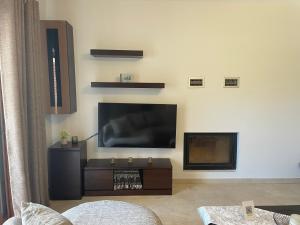 a living room with a flat screen tv and a fireplace at Villa Melydron in Nafplio