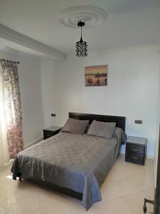 Un dormitorio con una cama grande y una lámpara de araña. en Apartment Corniche Ksar Sgher, en Alcazarseguir