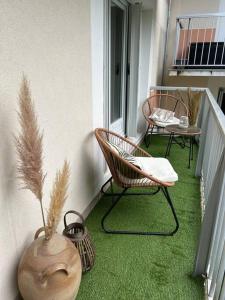 einen Balkon mit zwei Stühlen und einer Vase mit Pflanzen in der Unterkunft Appartement spacieux 6 personnes in Magny-les-Hameaux