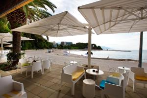 een restaurant met witte stoelen en parasols op het strand bij Apartments Zenta in Split