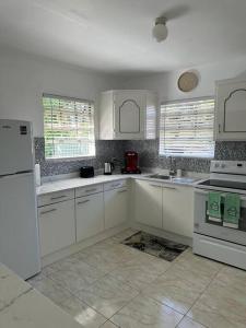 La cuisine est équipée de placards blancs et d'un réfrigérateur blanc. dans l'établissement Ottie-Newly Renovated, 5 min from beach, à Saint James