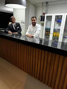 two men in suits are standing at a counter at LEON MARIA HOSPEDAGENS - Smart Flat Hotel e Residence in Mogi das Cruzes