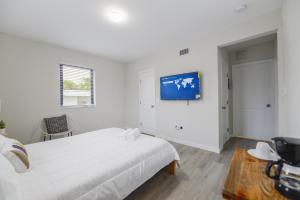 um quarto branco com uma cama e uma televisão na parede em Quiet Studio Near Calle Ocho in Miami em Miami