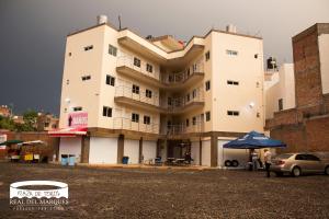 un grand bâtiment blanc avec une voiture garée devant. dans l'établissement Real Plaza de Toros, à San Juan de los Lagos