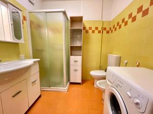 a bathroom with a toilet sink and a washer at Bright wide flat, 130m from the beach with shared pool in Porto Santa Margherita di Caorle