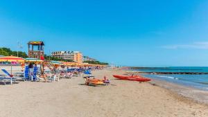 a beach with a bunch of chairs and umbrellas at Bright wide flat, 130m from the beach with shared pool in Porto Santa Margherita di Caorle