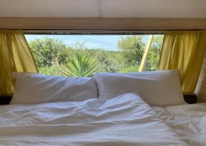 a bed with white sheets and pillows in front of a window at Três figos Caravan in São Luis