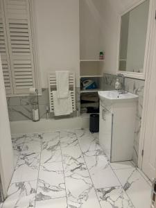 a white bathroom with a sink and a mirror at Grand Tulse Hill Villa in London