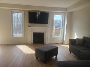 a living room with a fireplace and a flat screen tv at Elegant 4 BR 3.5 Bath Oasis: Mins frm Coburg Beach in Cobourg