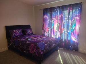 a bedroom with a purple bed and a curtain at Elegant 4 BR 3.5 Bath Oasis: Mins frm Coburg Beach in Cobourg