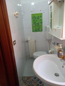 La salle de bains est pourvue d'un lavabo blanc et de toilettes. dans l'établissement Casa turistica Santa Lucia 25, à Regalbuto