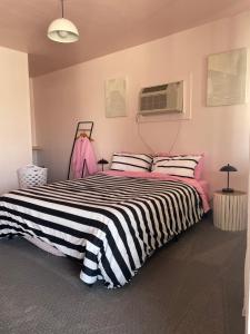 1 dormitorio con 1 cama con manta a rayas en blanco y negro en Rainbow Motel, en Greeley