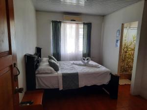 1 dormitorio con 1 cama con ventana y toalla en Hotel Golfito, en Golfito