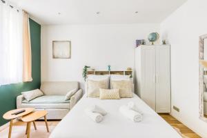 ein Schlafzimmer mit einem großen weißen Bett und einem Sofa in der Unterkunft Le Central Green Studio Parisien Cosy Proche Métro in Clichy
