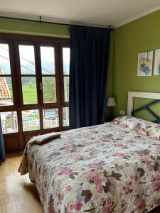 um quarto com uma cama com uma colcha floral e janelas em La Casina de Niembro em Niembro