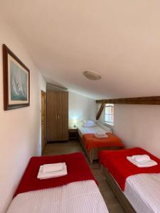 two beds in a small room with red sheets at Apartamenty Cegiełka in Gąski