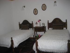 a bedroom with two beds and a clock on the wall at Casa Campo do Telhado in Caldelas