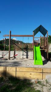 a playground with a green slide and swings at Casa Campo do Telhado in Caldelas
