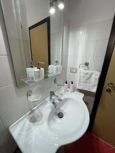 ein weißes Badezimmer mit einem Waschbecken und einem Spiegel in der Unterkunft Andi's Apartment 2 in Gjirokastër