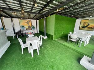 Habitación verde con mesas y sillas blancas y suelo verde en HOTEL AVICTORIA en Tonsupa
