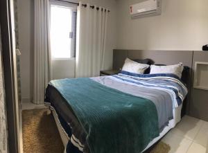 sypialnia z łóżkiem z niebieskim kocem i oknem w obiekcie Aconchego em Criciúma/SC w mieście Criciúma