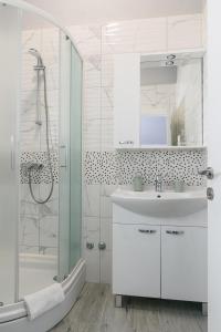 een witte badkamer met een wastafel en een douche bij Rooms Anna in Trogir