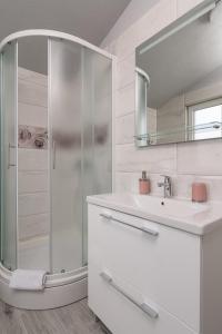 een witte badkamer met een douche en een wastafel bij Rooms Anna in Trogir