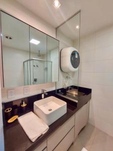 a bathroom with a sink and a large mirror at Luxury Collection - Elegância com Quarto Privativo in Campo Grande