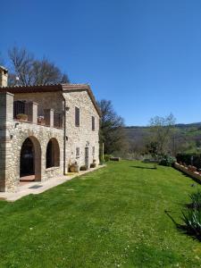 una antigua casa de piedra con un gran patio en La Piccola fattoria en Todi