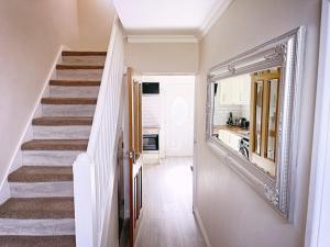 a hallway with a staircase with a mirror on the wall at Entire 3 Bed Home in Oldham in Oldham