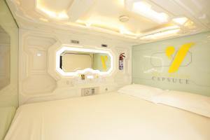 a white bed in a room with a mirror at The Yellow Capsule Hotel Close to Airport in Cancún