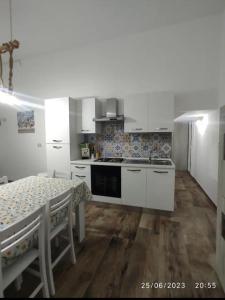 a kitchen with white cabinets and a table with chairs at U Feriu home in Avola +17 photos