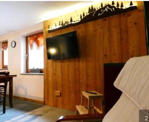 ein Wohnzimmer mit einem TV an einer Holzwand in der Unterkunft Maison L’Abri in Introd