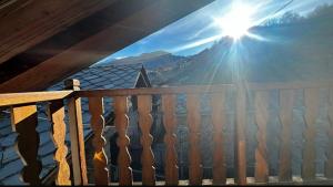einen Holzbalkon mit der Sonne am Himmel in der Unterkunft Maison L’Abri in Introd