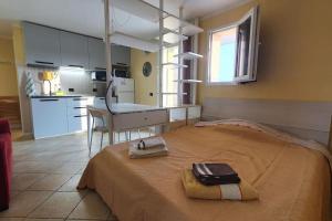 a bedroom with a bed with a desk and a kitchen at Monolocale ultimo piano con terrazzo e posto auto in Zola Predosa